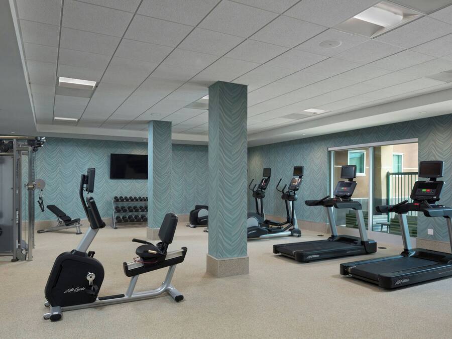Un gimnasio con cintas de correr, elípticas y máquinas de pesas.