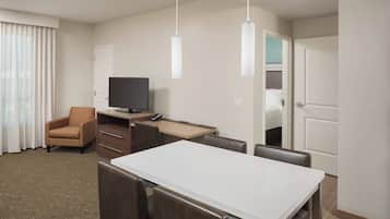 Una habitación de hotel con cama, escritorio, computadora, silla, televisor y mesa de comedor.