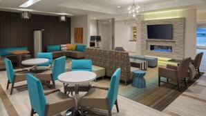 A modern lounge area with seating arrangements, a flat-screen TV, and a fireplace. - Residence Inn by Marriott Ontario Rancho Cucamonga (Rancho Cucamonga)