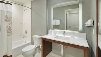 Un baño moderno con ducha, inodoro y tocador con espejo.
