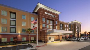 A multi-story hotel with a modern design, featuring a prominent entrance and a parking area with several cars. - Residence Inn by Marriott Ontario Rancho Cucamonga (Rancho Cucamonga)