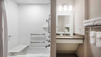 A modern bathroom with a bathtub, shower, and vanity with a mirror.
