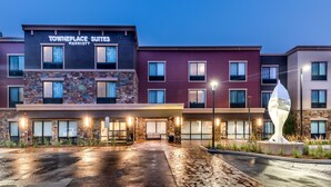 Un hotel de varios pisos con fachada de piedra, un acceso cubierto y un espacio exterior bien iluminado.