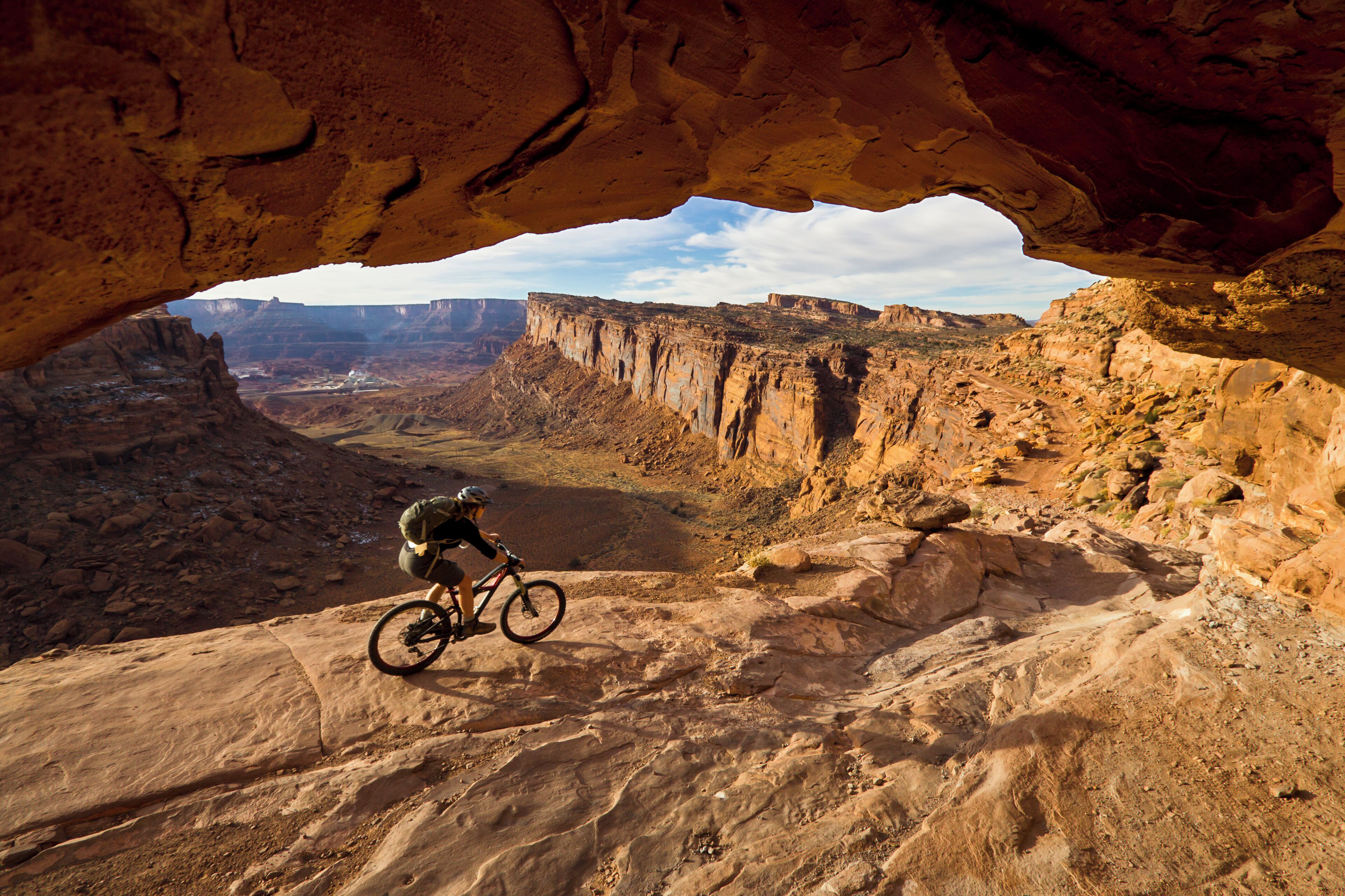 Un vététiste sur un sentier rocailleux, avec vue sur un canyon.