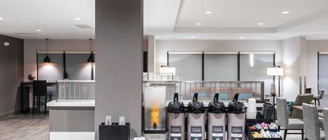 Un hall d’hôtel moderne doté d’un espace café, d’un coin salon et d’un comptoir d’accueil.