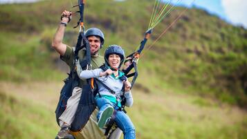 Una persona haciendo parapente con arnés y líneas de control.