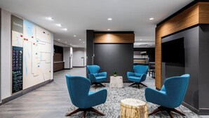 Un vestíbulo moderno con sillas azules, un mapa en la pared y un panel decorativo de madera.