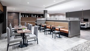 Un restaurante moderno con mesas, cabinas y una zona de bar, además de una pantalla de televisión.