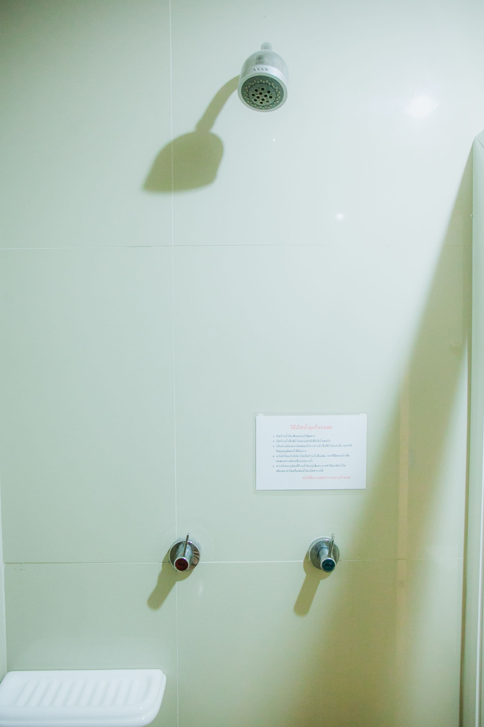 Un baño con ducha, inodoro y un cartel con texto.