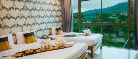 A hotel room with two beds, a large window with a mountain view, and a patterned wallpaper.