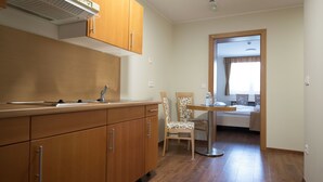 Cocina compacta con armarios de madera y comedor con una silla y una mesa.