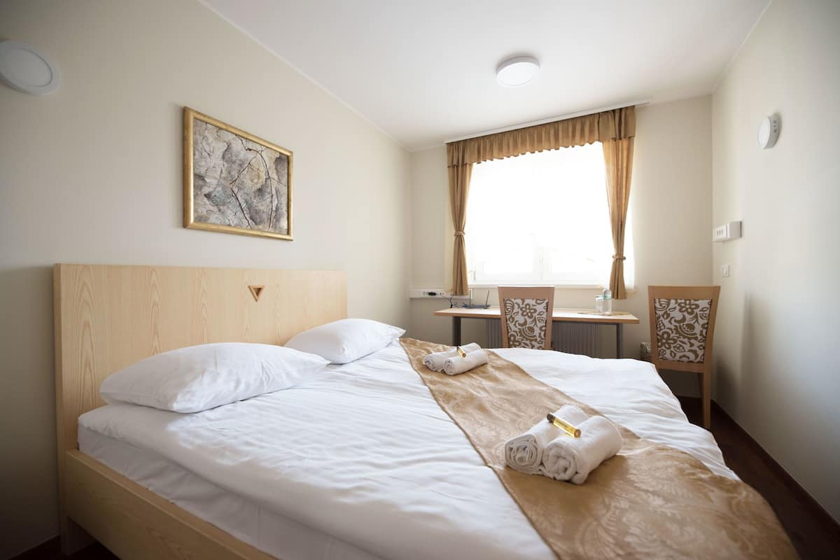 A hotel room with a large bed, a desk, and a chair.