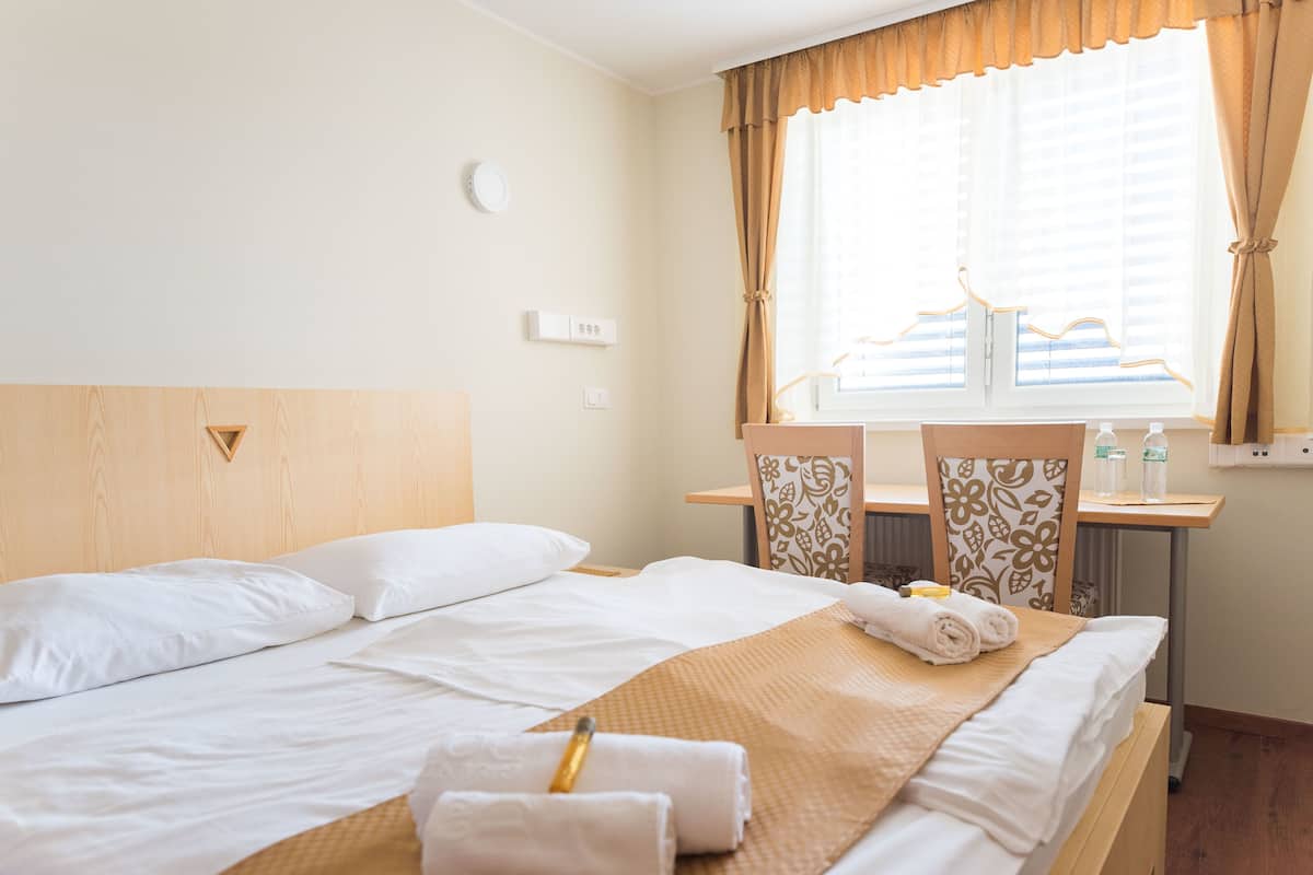 A hotel room with a bed, a desk, and a window with curtains.