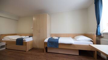 A room with two wooden beds, a wardrobe, and a desk.