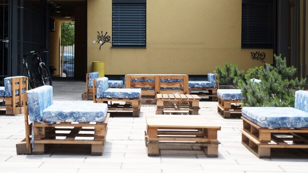 Un patio con muebles de madera y una pared amarilla.
