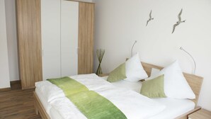 A bedroom with a bed, wooden wardrobe, and wall-mounted bird sculptures. - Störtebeker Suite, Germany (Glowe)