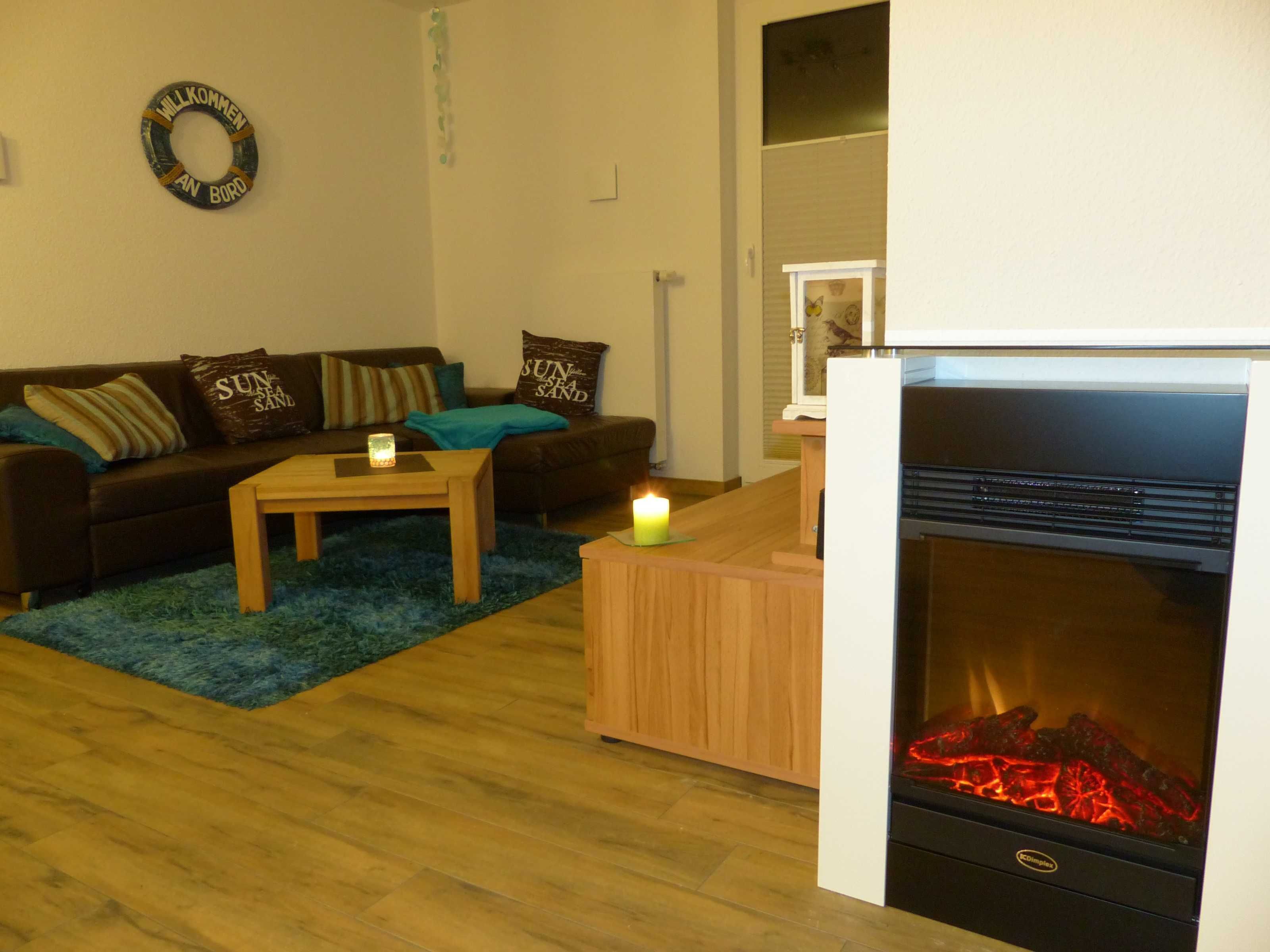 A living room with a sofa, a coffee table, a fireplace, and a wall-mounted welcome sign.