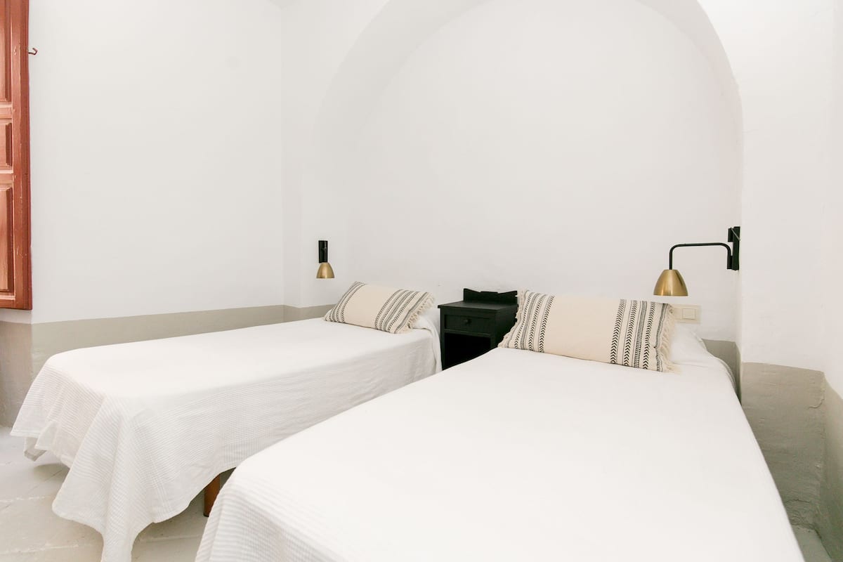 A room with two single beds, a small table, and a nightstand.