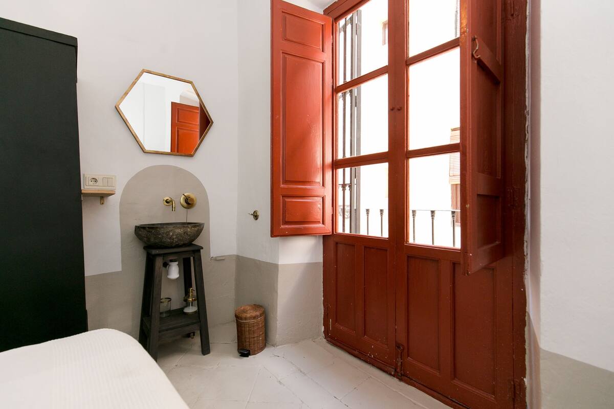 A bathroom with a large mirror, a sink, and a door with a window.