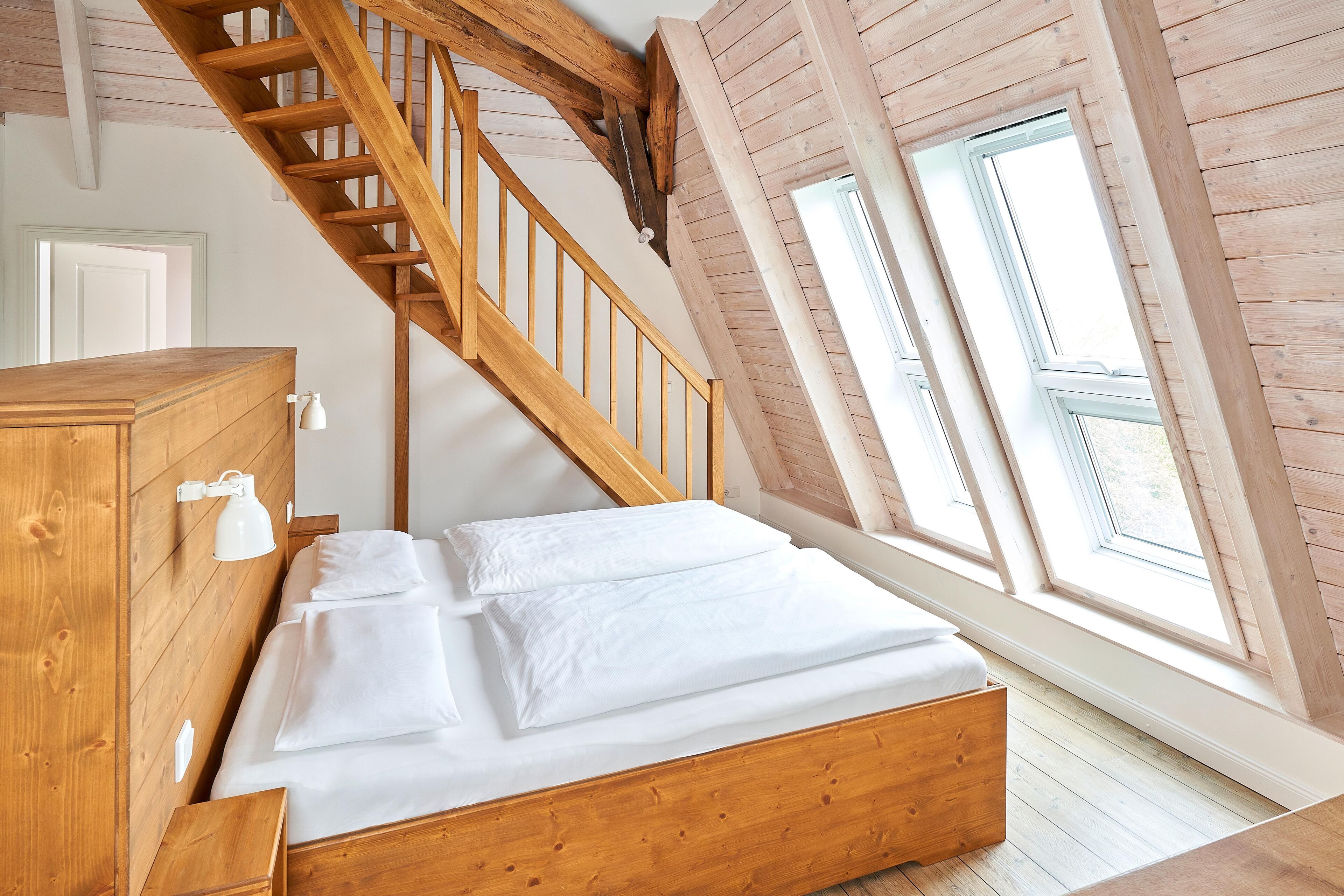 Une chambre à coucher avec un lit en bois, une commode en bois et un escalier en bois.