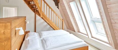 Une chambre à coucher avec un lit en bois, une commode en bois et un escalier en bois.