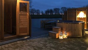 Ett badkar av trä med lyktor, en träveranda och en träbyggnad med en dörr.