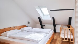 Une chambre à coucher avec un lit en bois, un berceau, un puits de lumière et un radiateur.