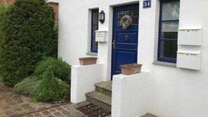 Un bâtiment blanc avec une porte bleue, portant le numéro 34, et deux petites fenêtres.