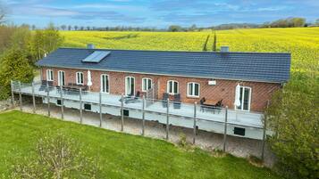 Ein Ziegelhaus mit Balkon mit Blick auf ein Feld voller gelber Blumen.