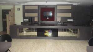 Un área de recepción con mostrador, dos televisores y un expositor de vidrio decorativo.