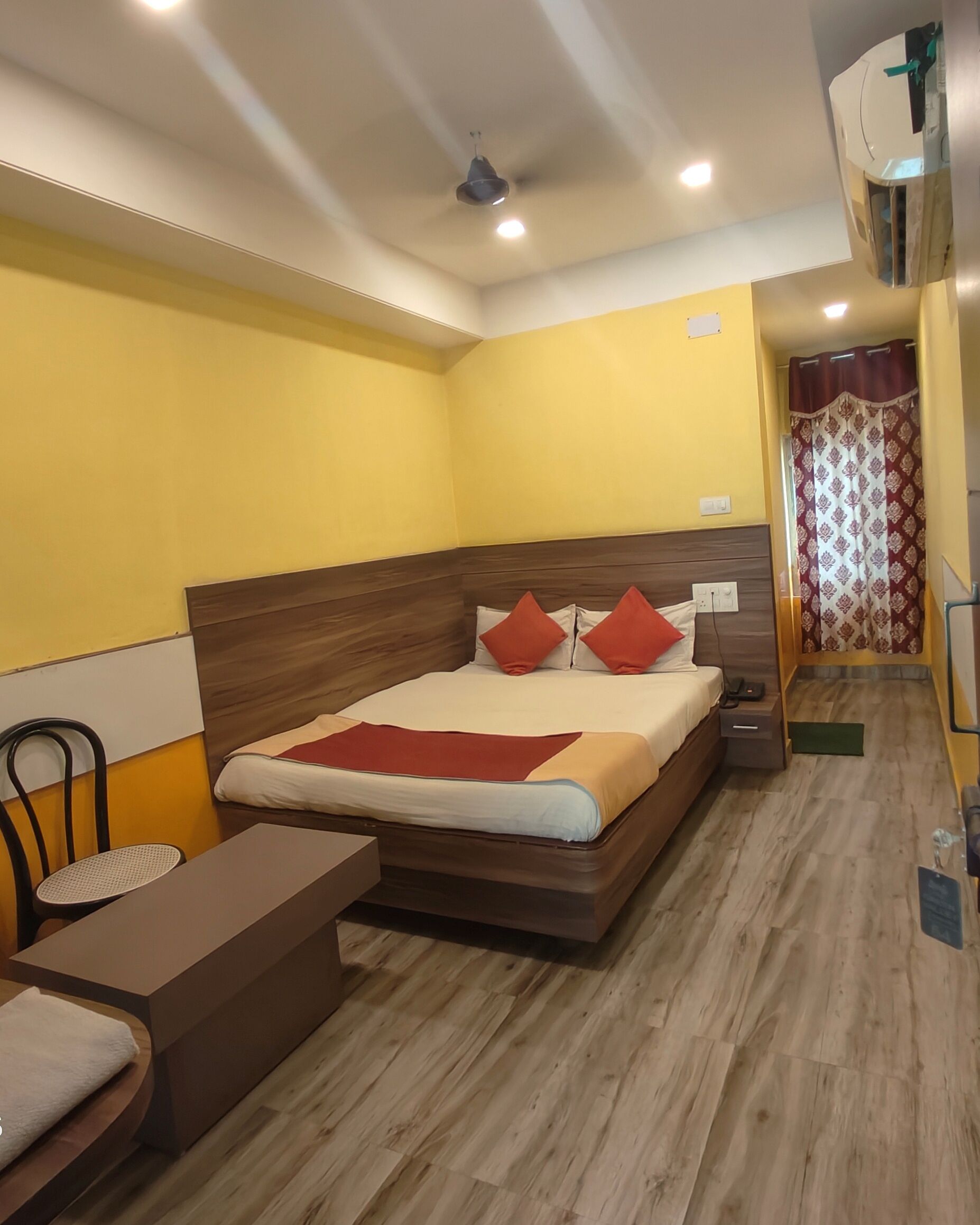 A hotel room with a wooden bed, a small table, and a chair.