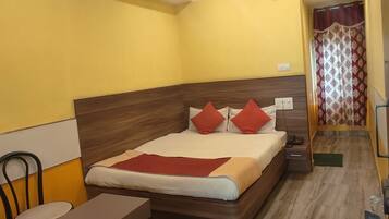 A hotel room with a wooden bed, a small table, and a chair.