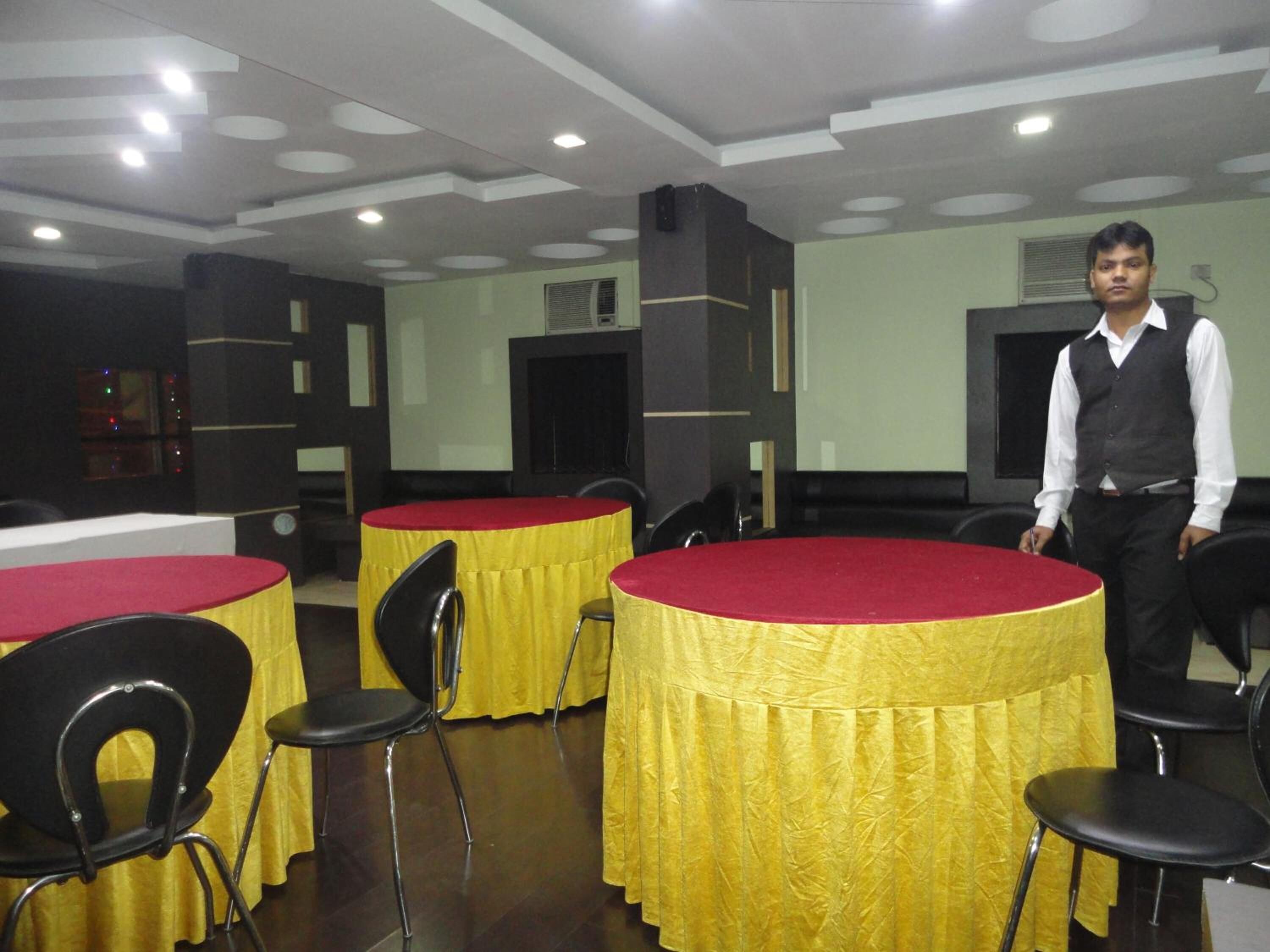A conference room with round tables covered in yellow tablecloths and black chairs.