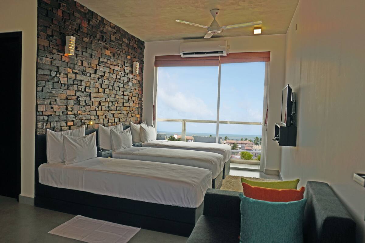 Un dormitorio moderno con dos camas, una pared de piedra, un ventanal con vistas y un ventilador de techo.