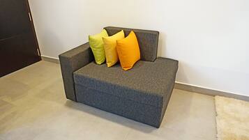 A gray sofa with three pillows in yellow, green, and orange colors.