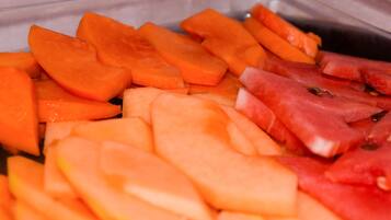 A container with sliced fruits including cantaloupe and watermelon.