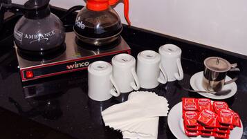 Eine Küchenarbeitsplatte mit Kaffeemaschine, Wasserkocher, weißen Tassen, einer Servierplatte mit Gewürzen und einem Löffel.