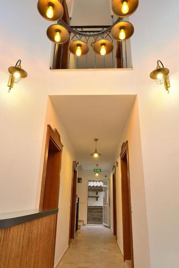 Un pasillo con mostrador de recepción de madera, una escalera y una lámpara en el techo.