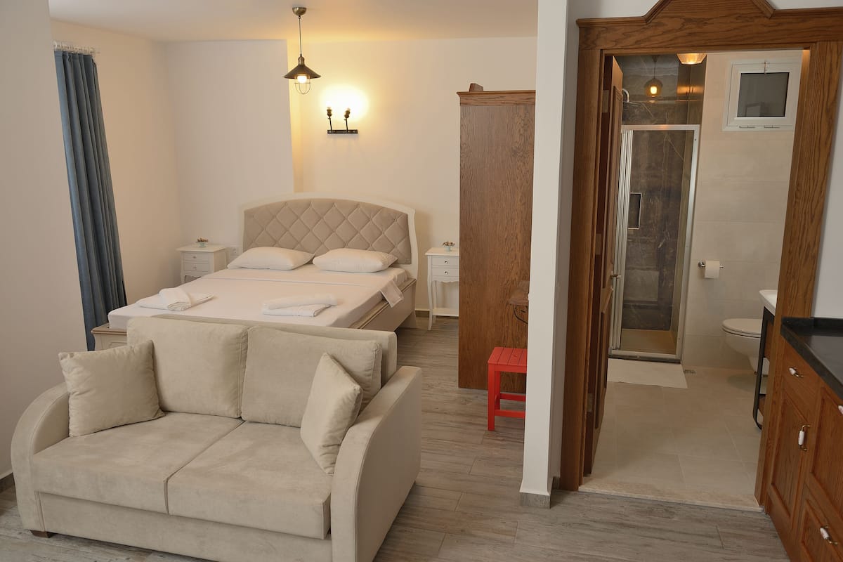 A bedroom with a bed, a sofa, a nightstand, and a wooden wardrobe.
