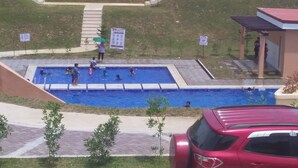 A swimming pool area with a red car parked nearby. - CLB-Vacation House for rent (Tagbilaran)