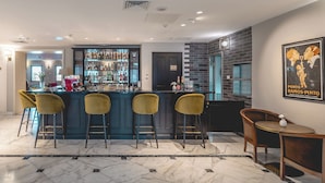 A bar area with a marble floor, bar stools, and a liquor display. - Edmond Luxury Hotel & Spa (Rosh Pinna)