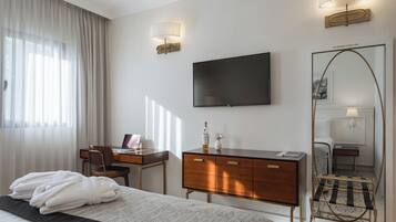 A hotel room with a bed, a desk, a dresser, a TV, and a large mirror.