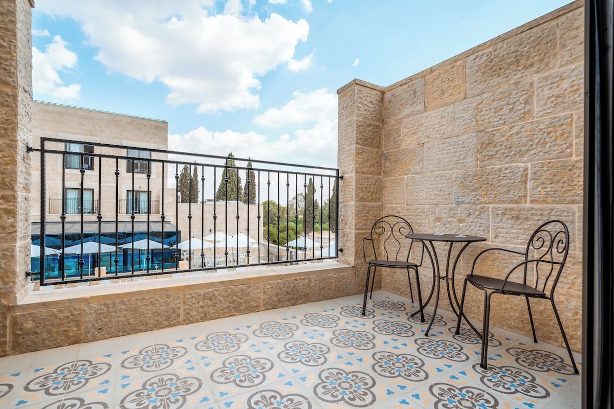 Un balcon avec un mur en pierre, une piscine et deux chaises en métal.