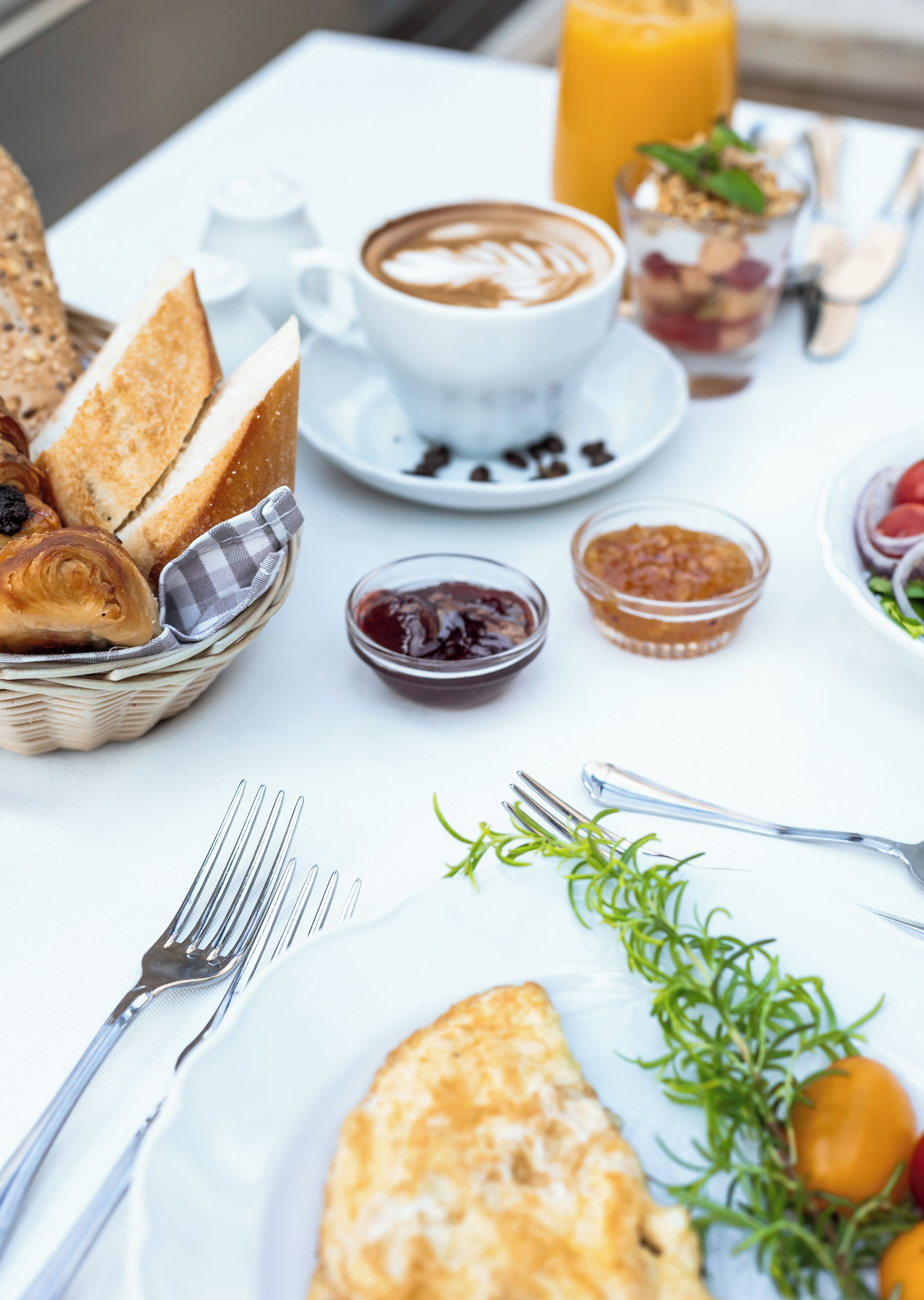 A breakfast setting with croissants, coffee, and various spreads on a table.
