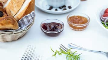 A breakfast setting with croissants, coffee, and various spreads on a table.