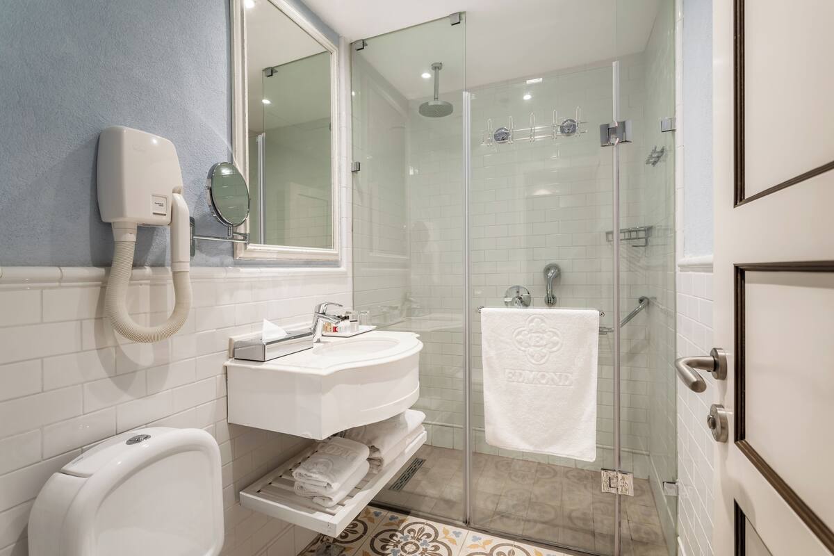 Une salle de bain moderne avec une douche à parois de verre, un lavabo blanc et une douchette à main.