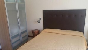 A bedroom with a bed, a wardrobe, and a nightstand. - Hotel Illi  (Massa)