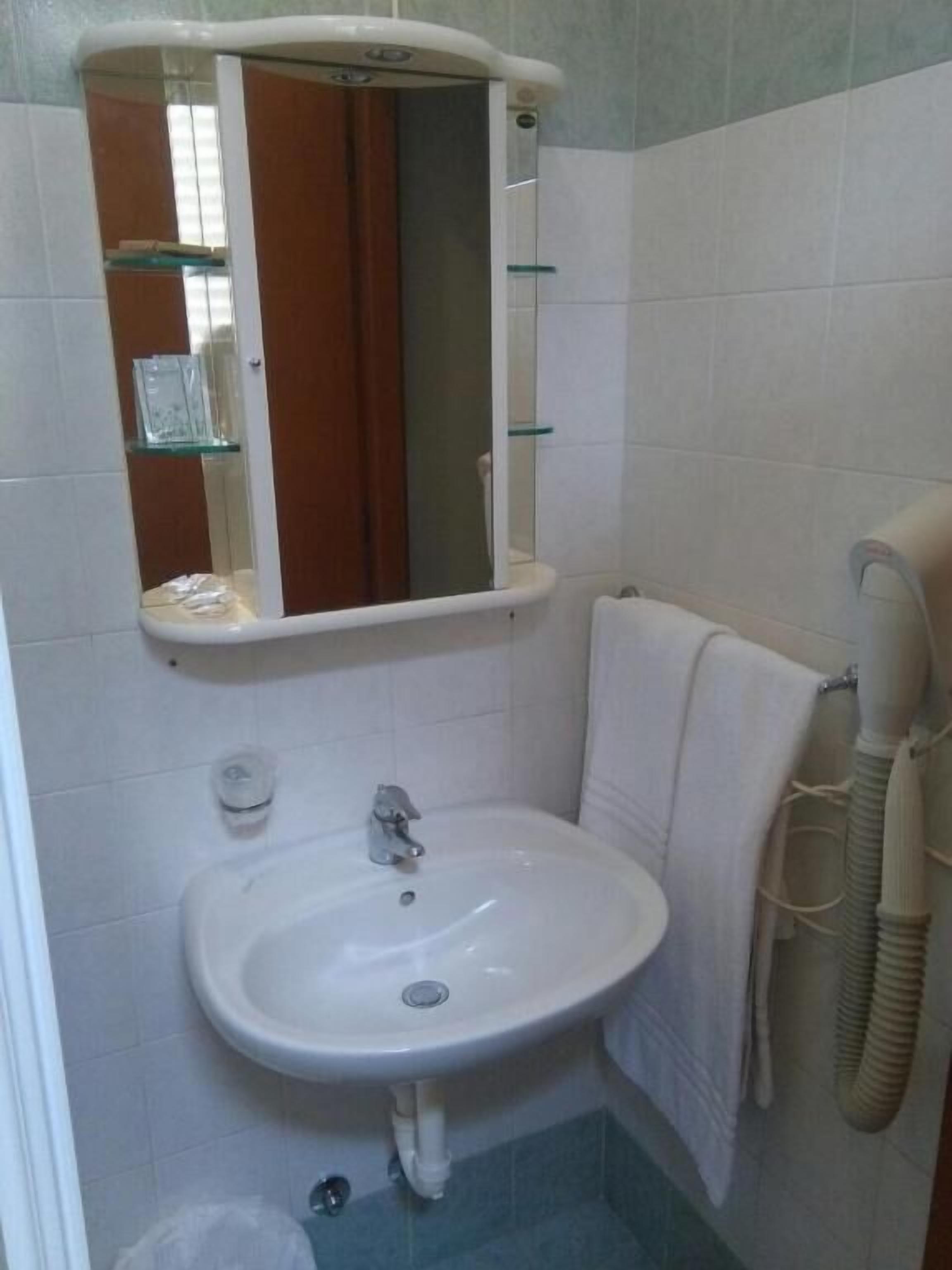 Ein Badezimmer mit einem weißen Waschbecken, einem Spiegel und einem Handtuchhalter.