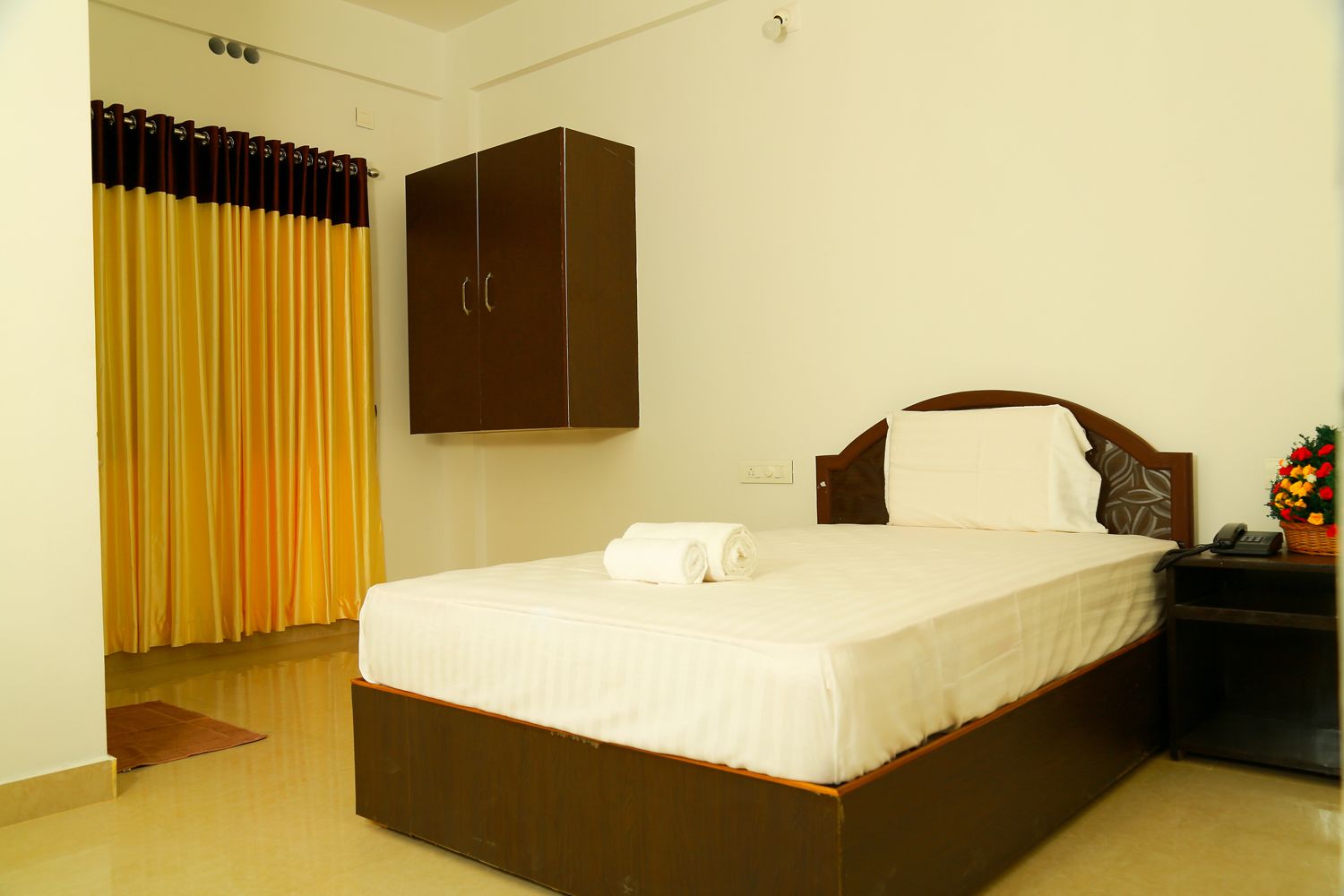 Una habitación de hotel con una cama grande, un armario, una mesita de noche y un teléfono.