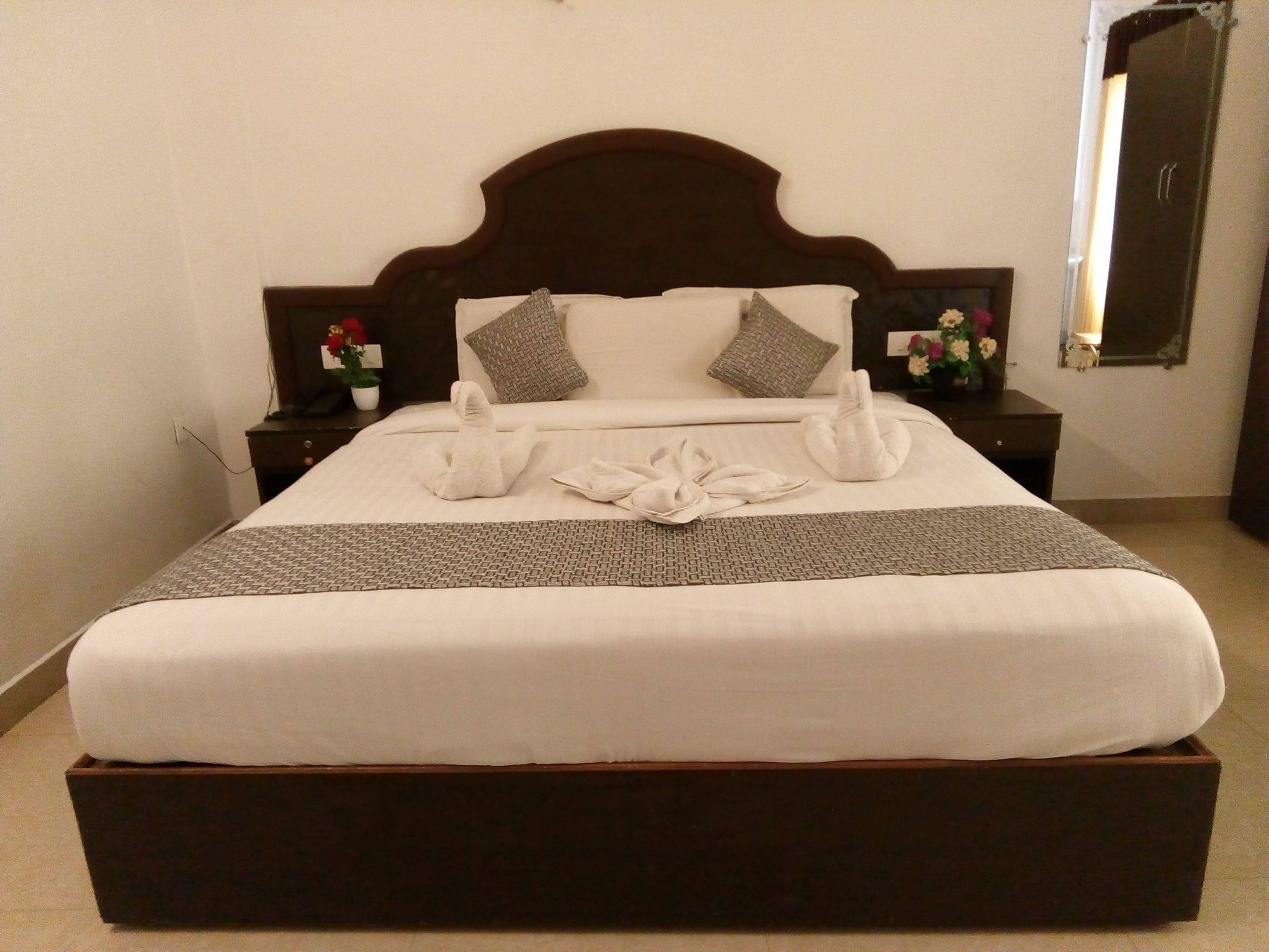 A neatly made bed with a dark headboard, white linens, and a patterned throw.